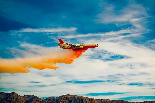 Avión lanza químicos para controlar fuego